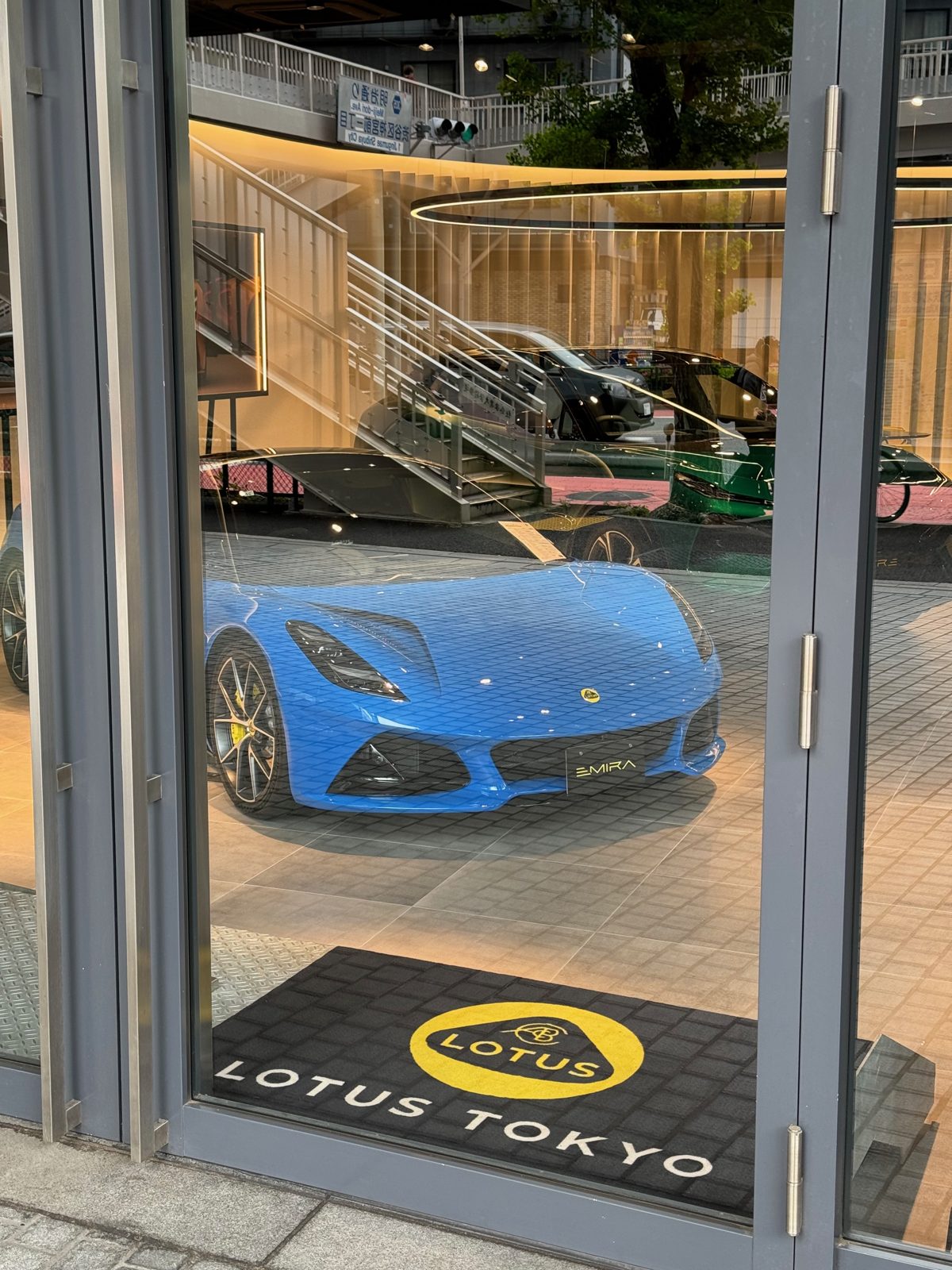 A blue Lotus Emira in the window of the Lotus Tokyo showroom in Harajuku